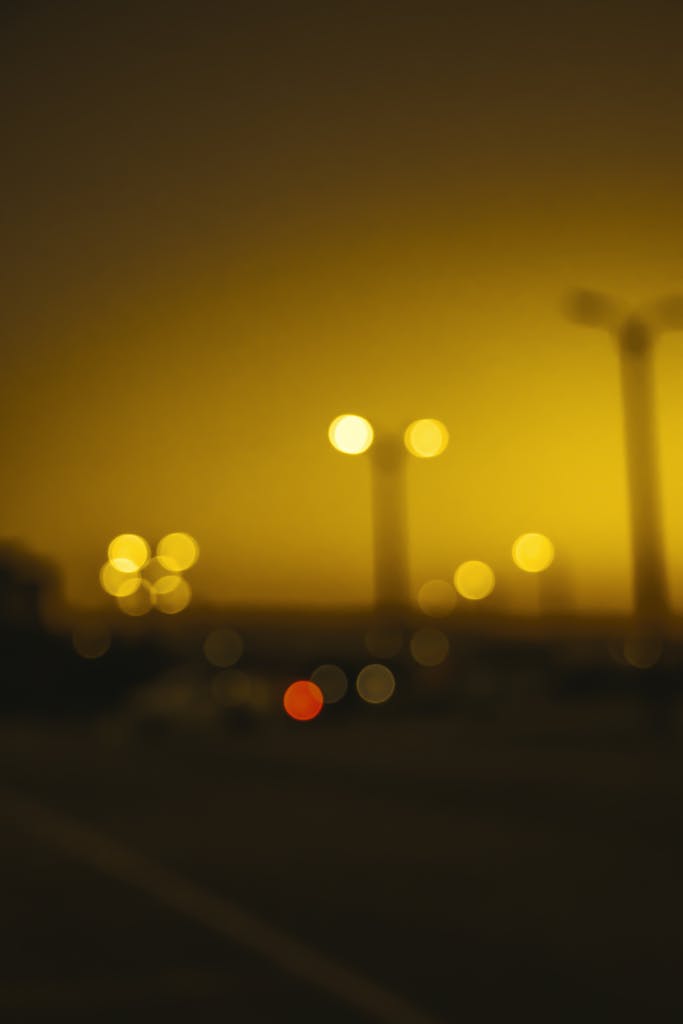 A soft-focus image of glowing street lights against a dusk sky, creating a warm bokeh effect.